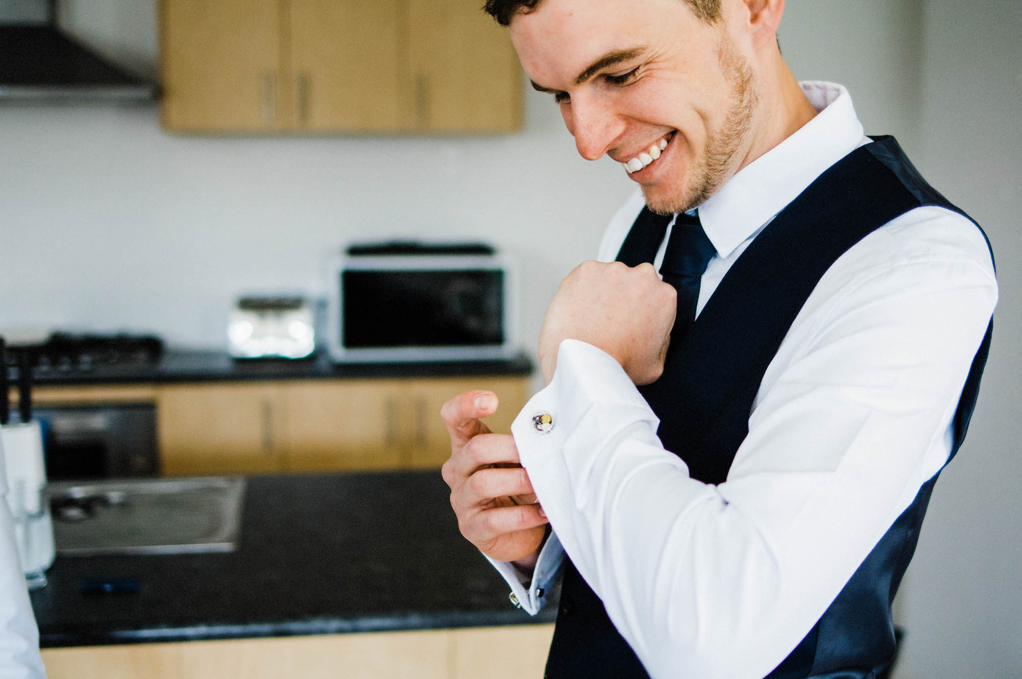 A photo of the Groom smiling at his custom cufflinks. 