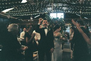 A photo of the groom cheering as he and the bride walk back down the aisle after their Bridgetown Wedding Ceremony
