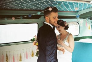 A photo of the bride & groom laughing together in a vintage Combi Van after their Bridgetown wedding