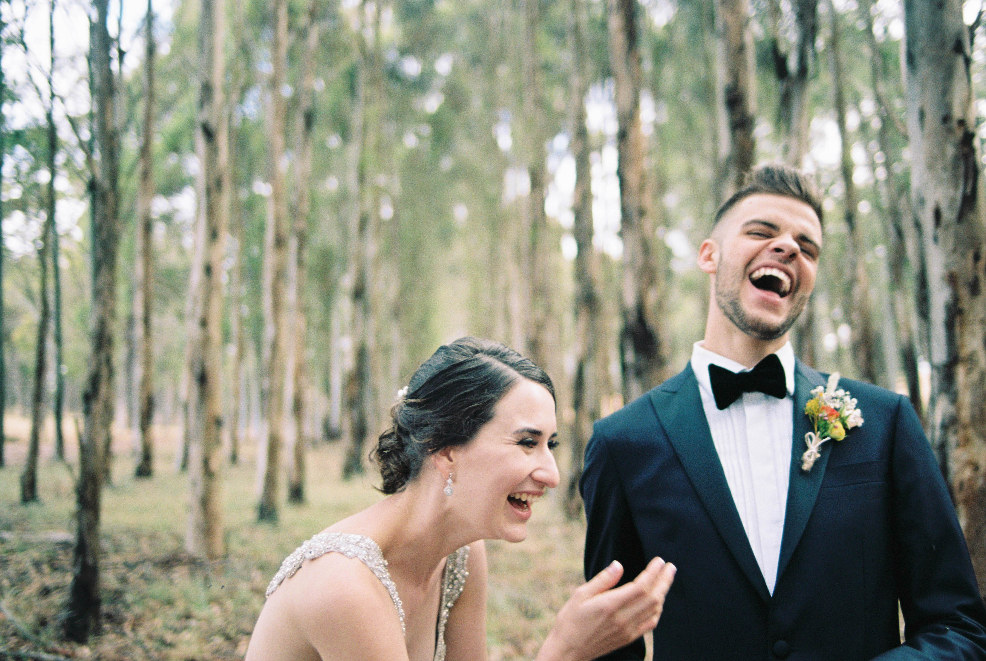 Candid wedding portraits of the bride and groom laughing in a blue gum plantation