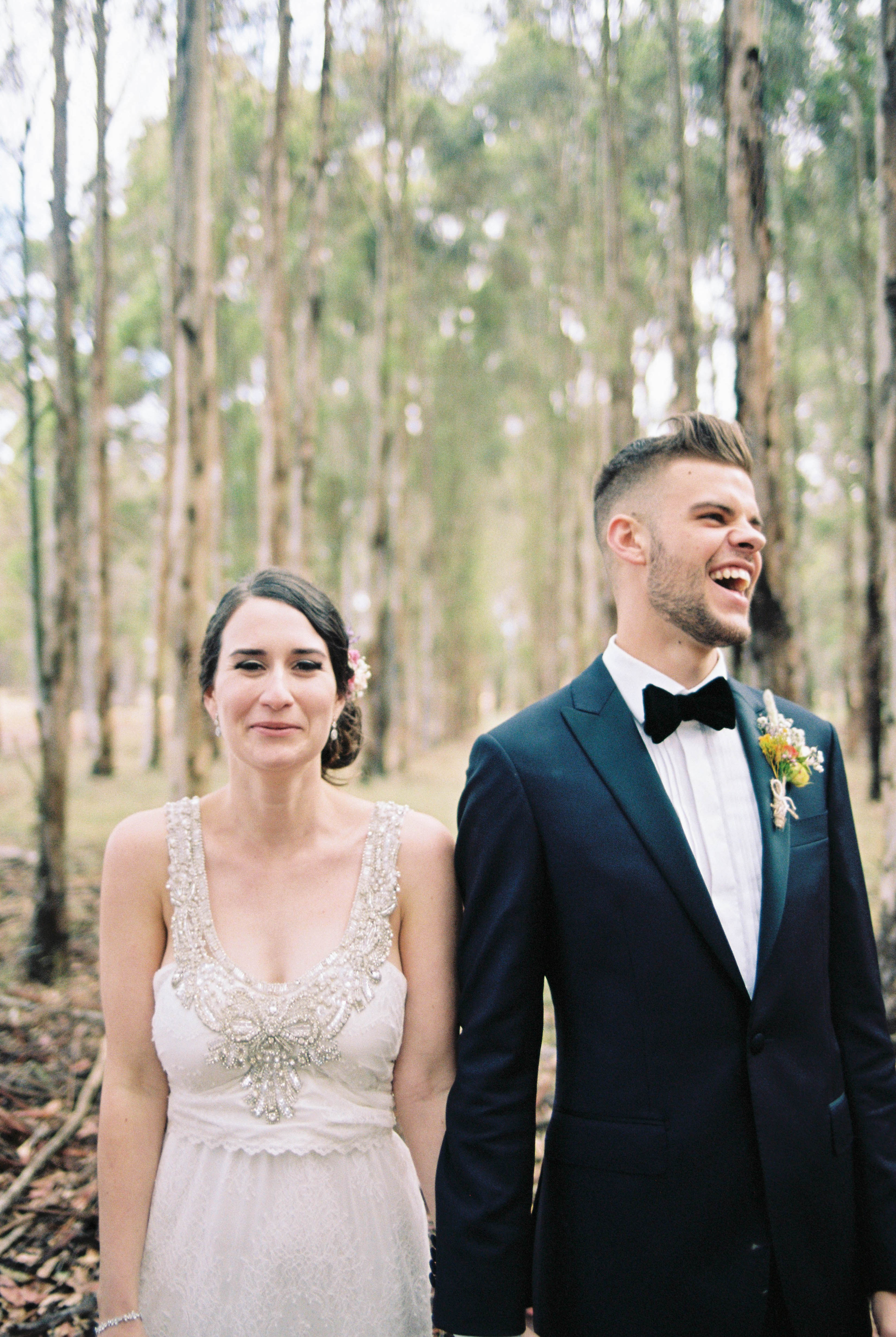A portrait of the bride and groom laughing in a blue gum plantation