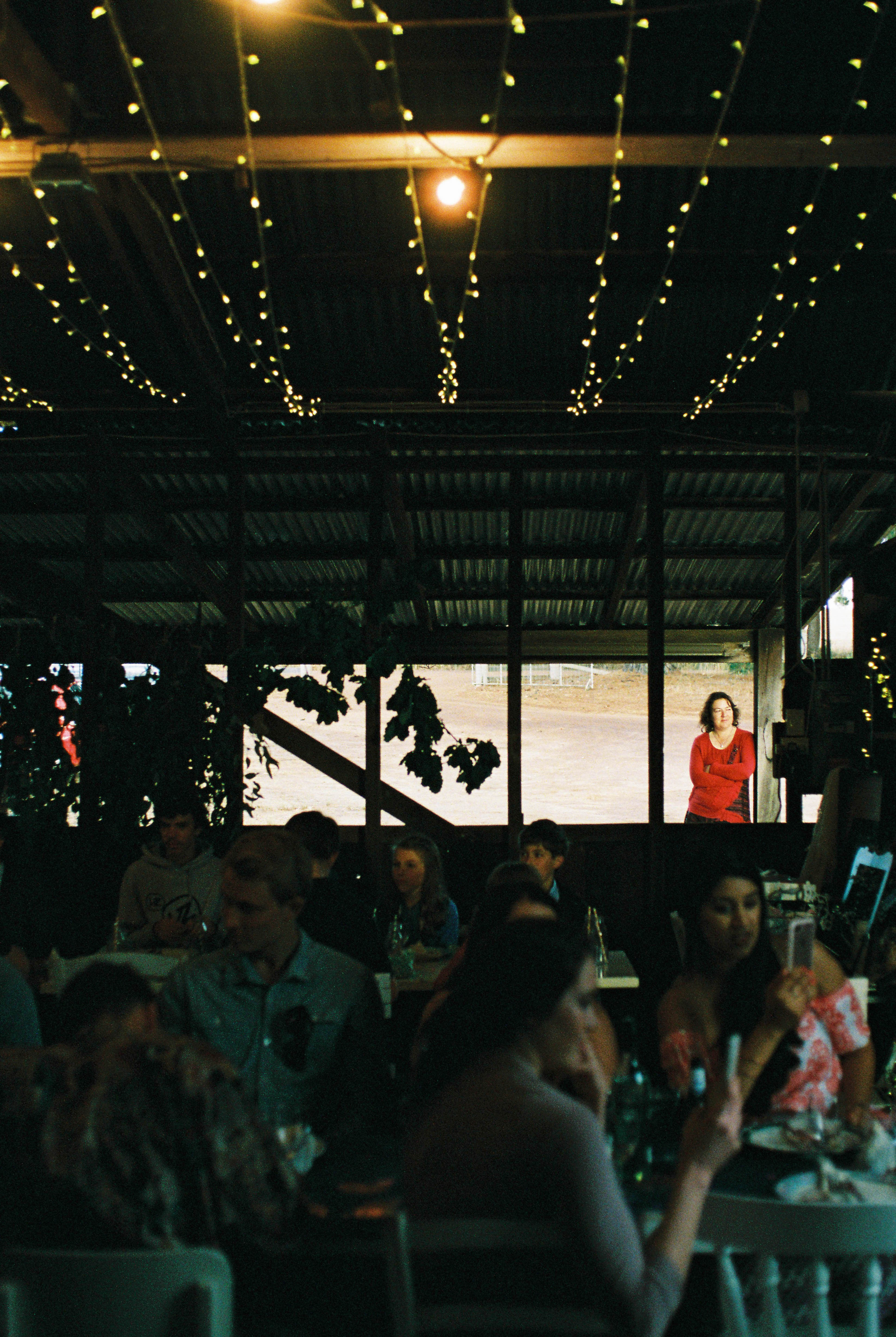 A striking wedding photo of a guest watching on from outside during a shearing shed wedding reception