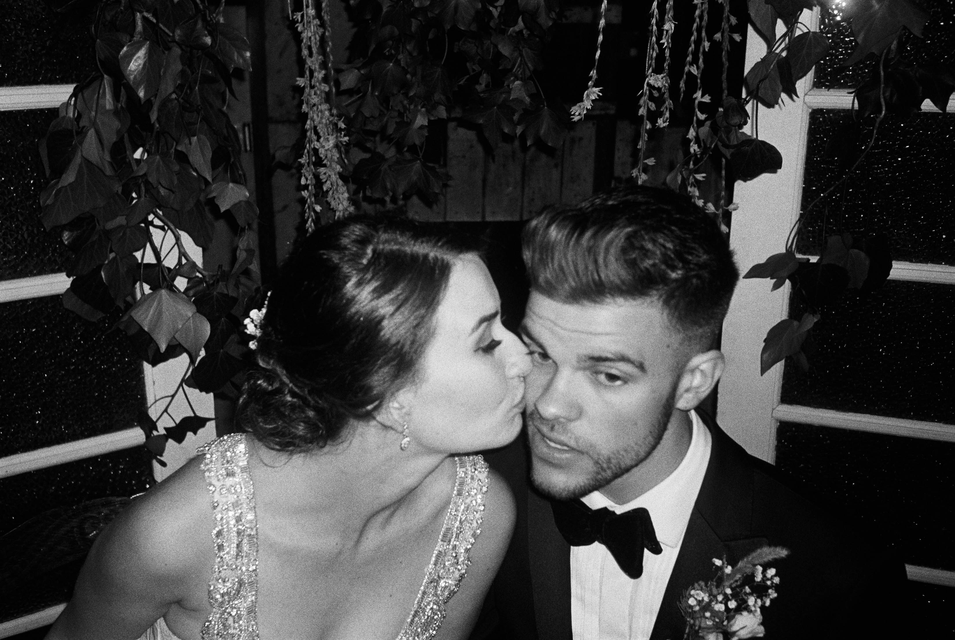 A fun black & white film wedding photo of the bride & groom during their wedding reception