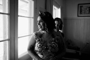 A black & white wedding photo of the bride's mum helping her with her dress.