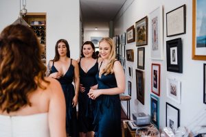 Documentary Wedding Photography of the bridesmaid's, who are wearing blue, reacting to seeing the bride in her dress for the first time.