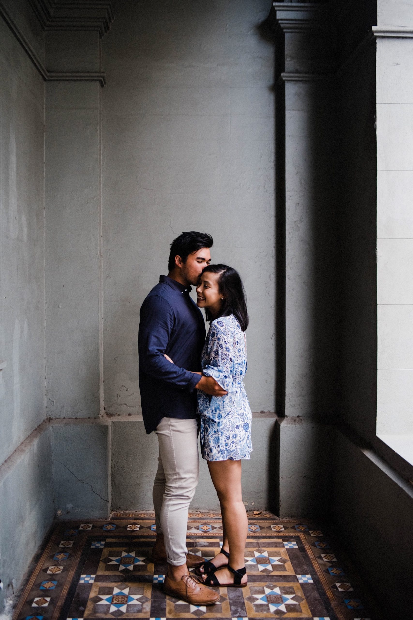 A romantic engagement photo of a young couple, standing in the courtyard of a heritage building in Fremantle.