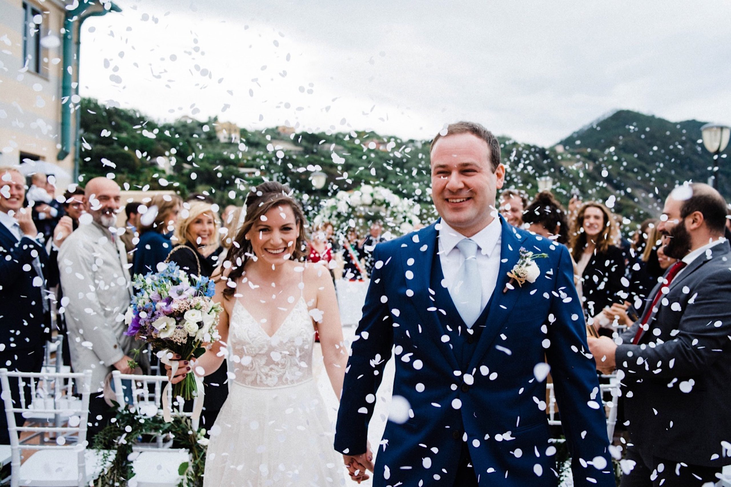 Italian Riviera Destination Wedding Photography of the bride & groom walking back down the aisle as guests throw confetti all around them.