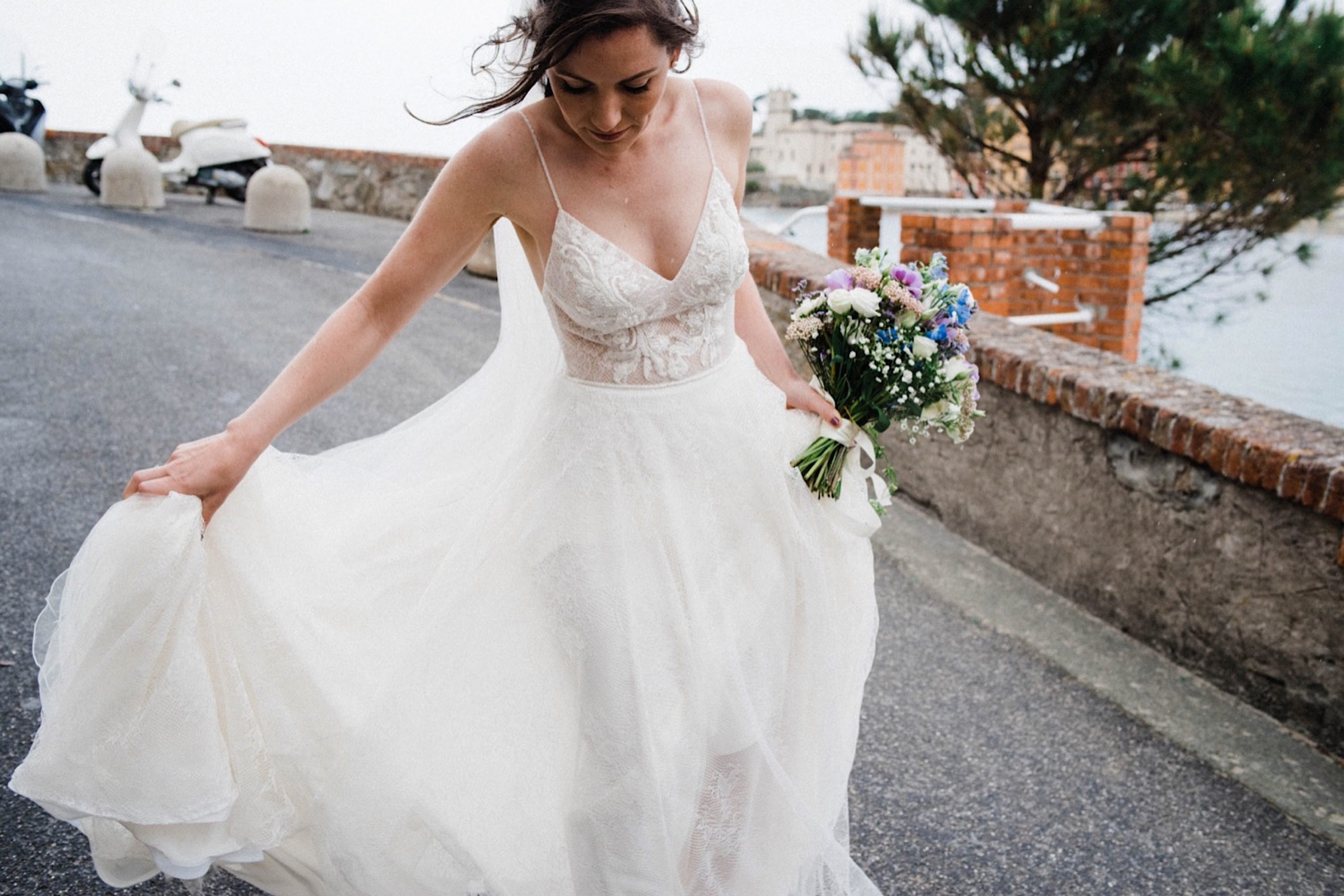 Natural Destination Wedding Photography of a bride adjusting her Flora Bridal Dress on the streets of Sestri Levante.