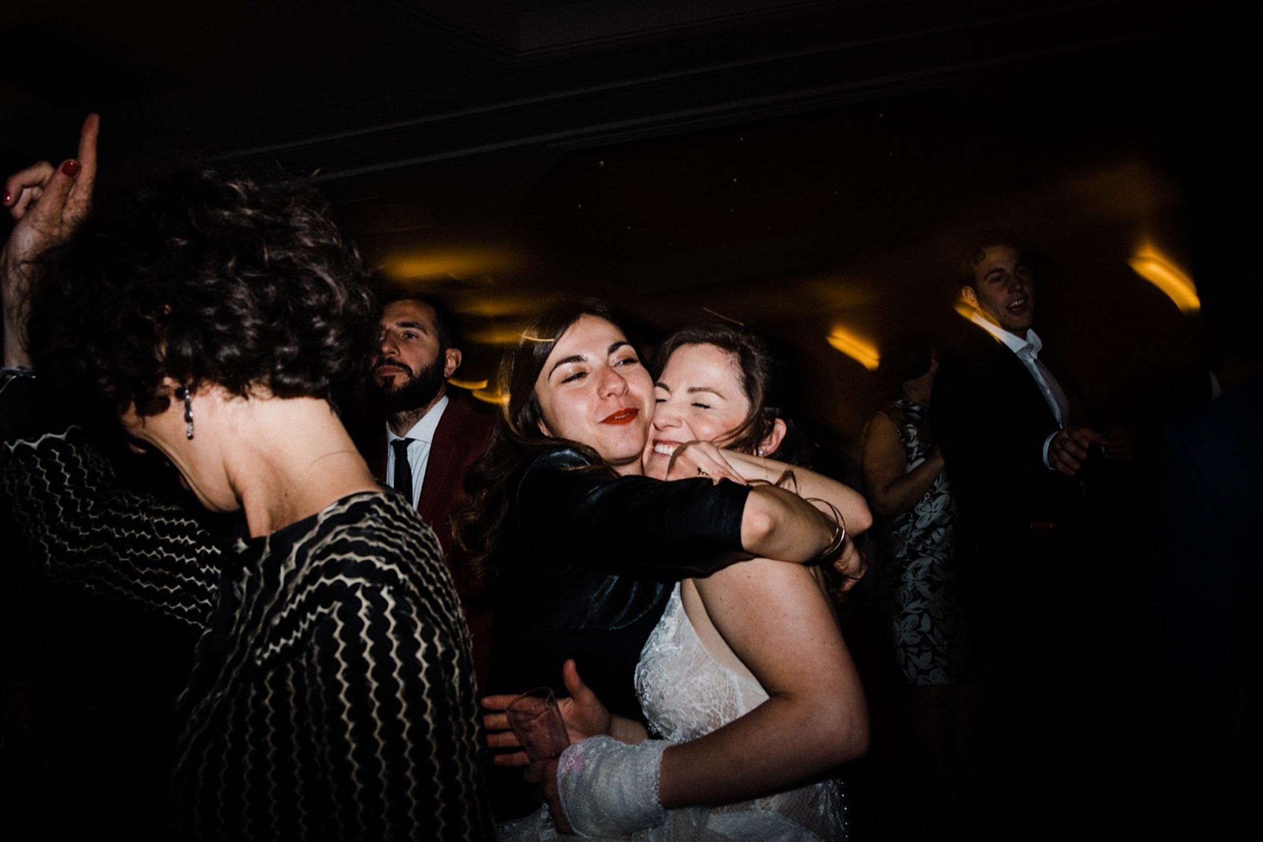 Candid Wedding Photography of a guest hugging the bride on the dance floor.