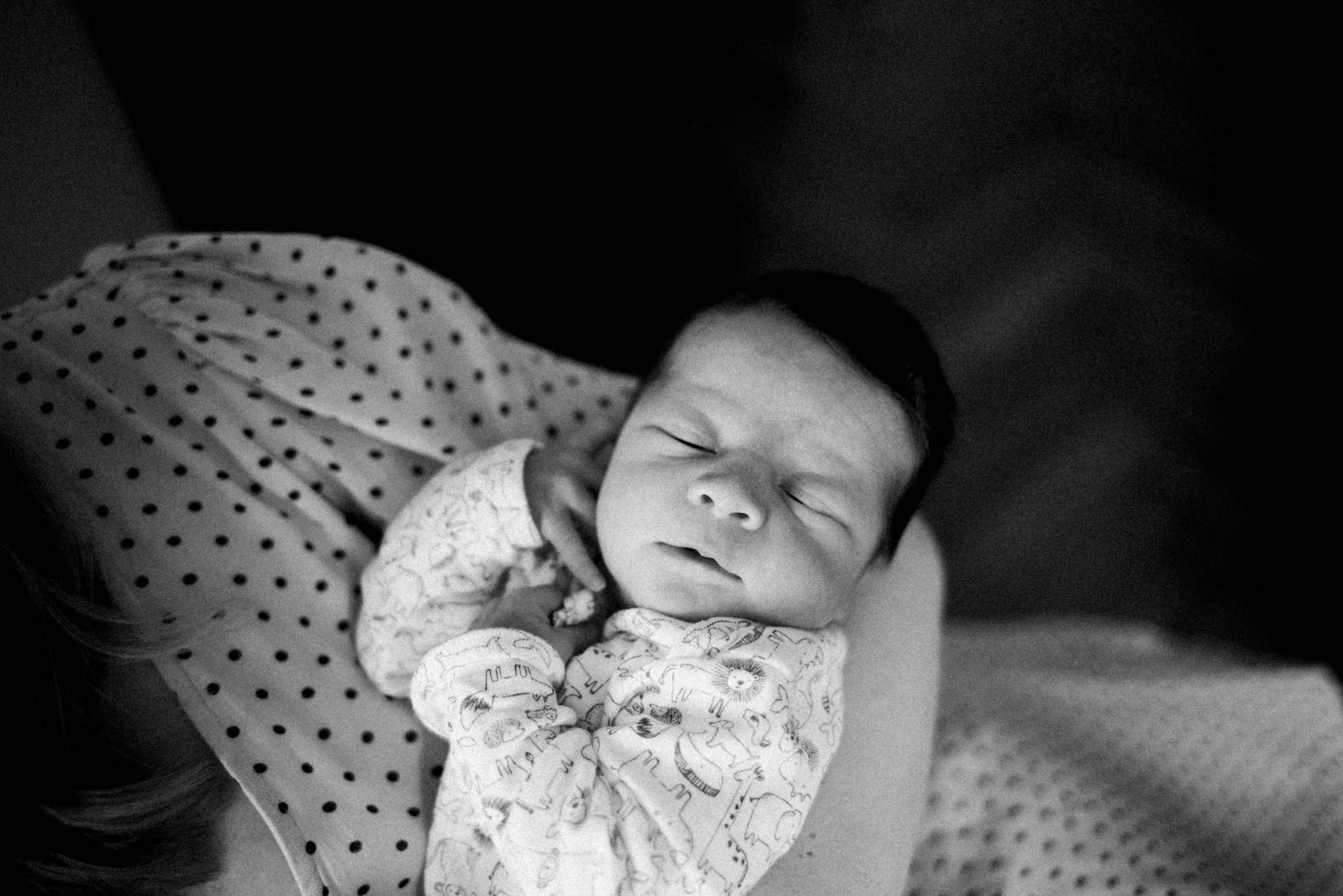 Black and White photo of a newborn baby in his Mum's arms, taken at home in Milan, Italy.