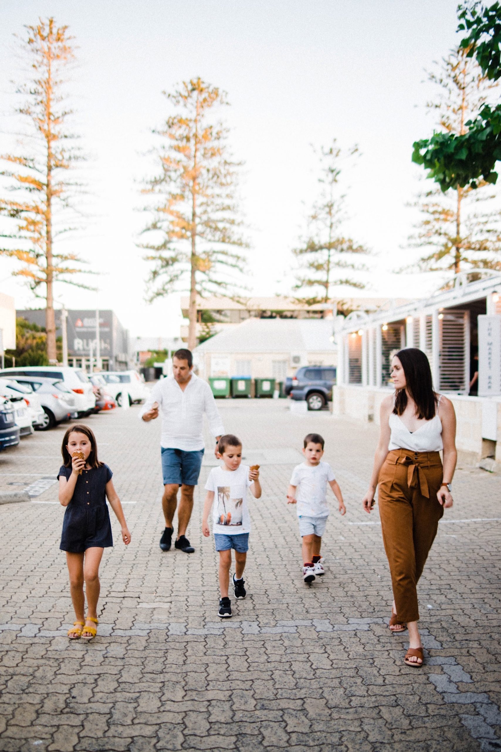 A natural portrait of a family of 5 walking through the streets of Fremantle, with two of the kids and the Dad eating ice creams.
