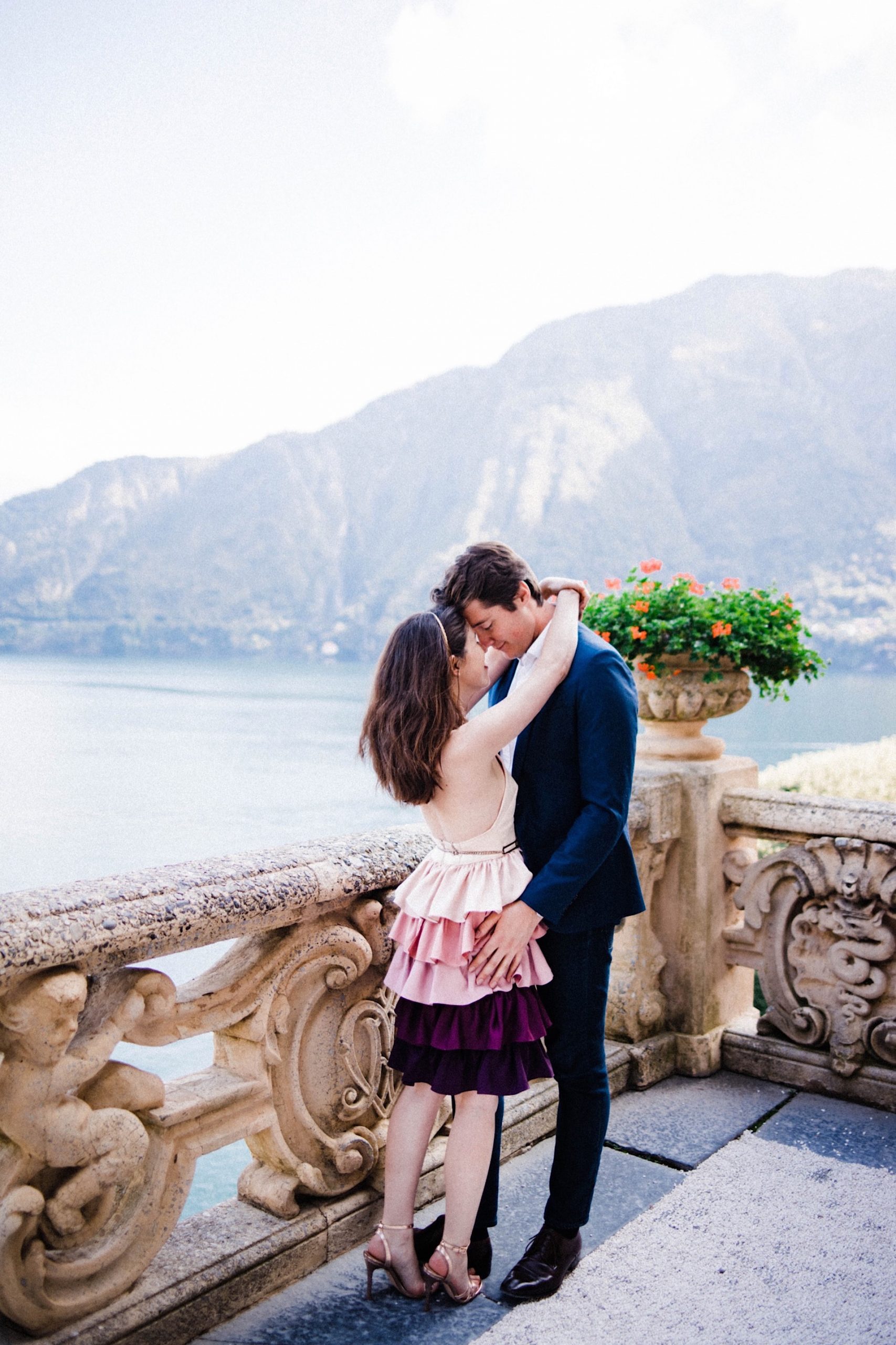 Villa Balbianello Portrait Photography of a couple standing against the Villa's main lookout over Lake Como and its surrounding mountains.
