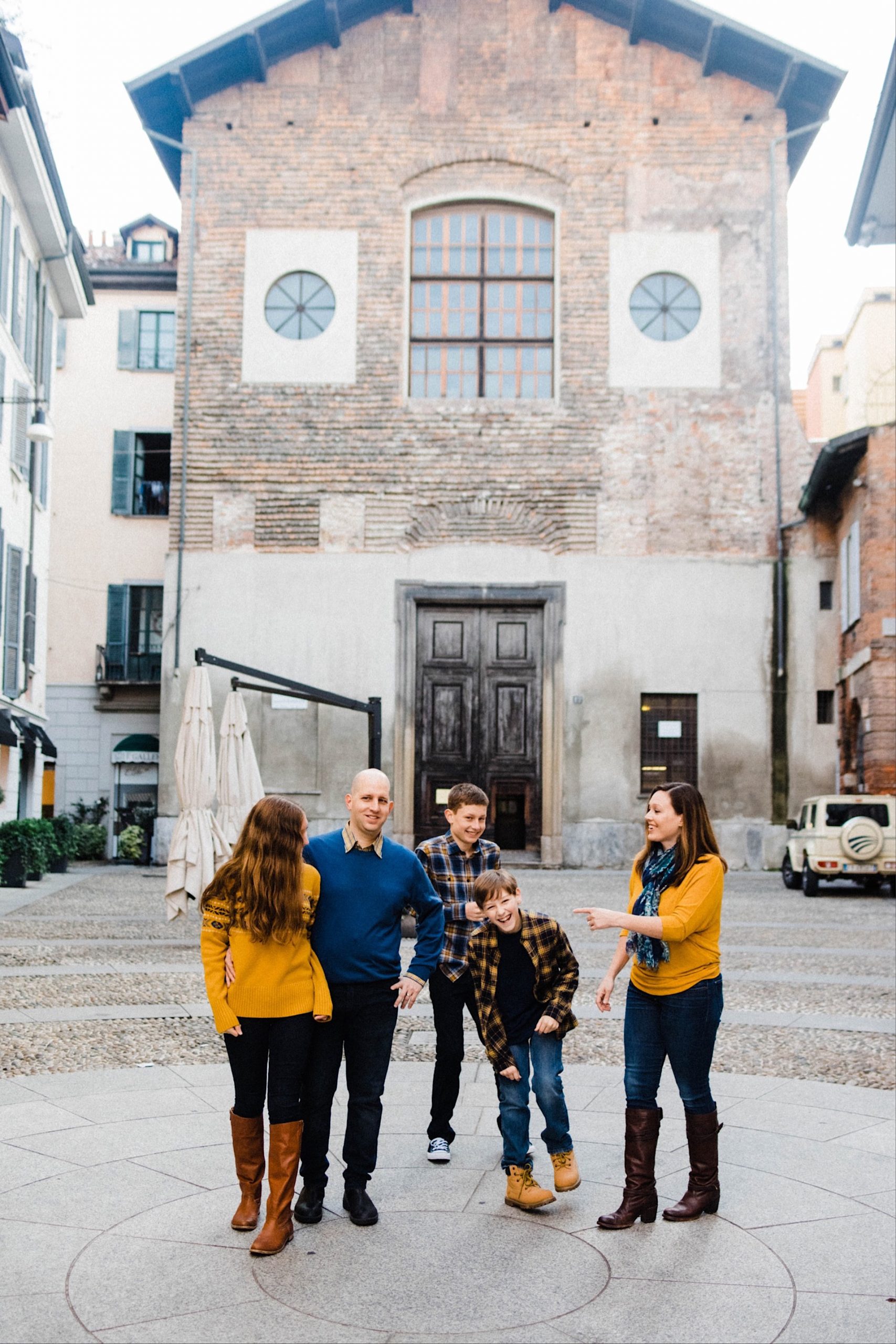 Portrait photo of a family all laughing, standing in a piazza in Milan.