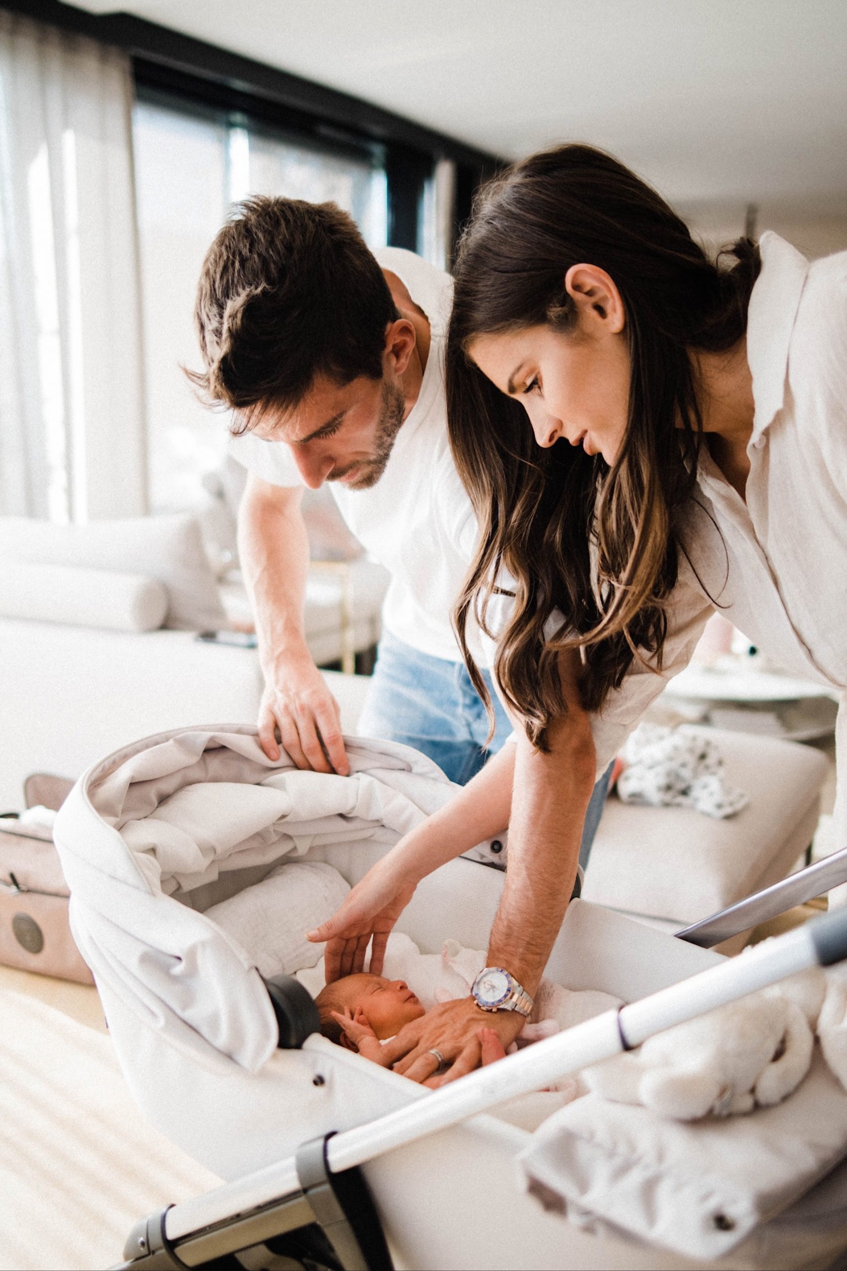 A portrait image of a Mum and Dad calming their newborn who's lying in her Stokke stroller.