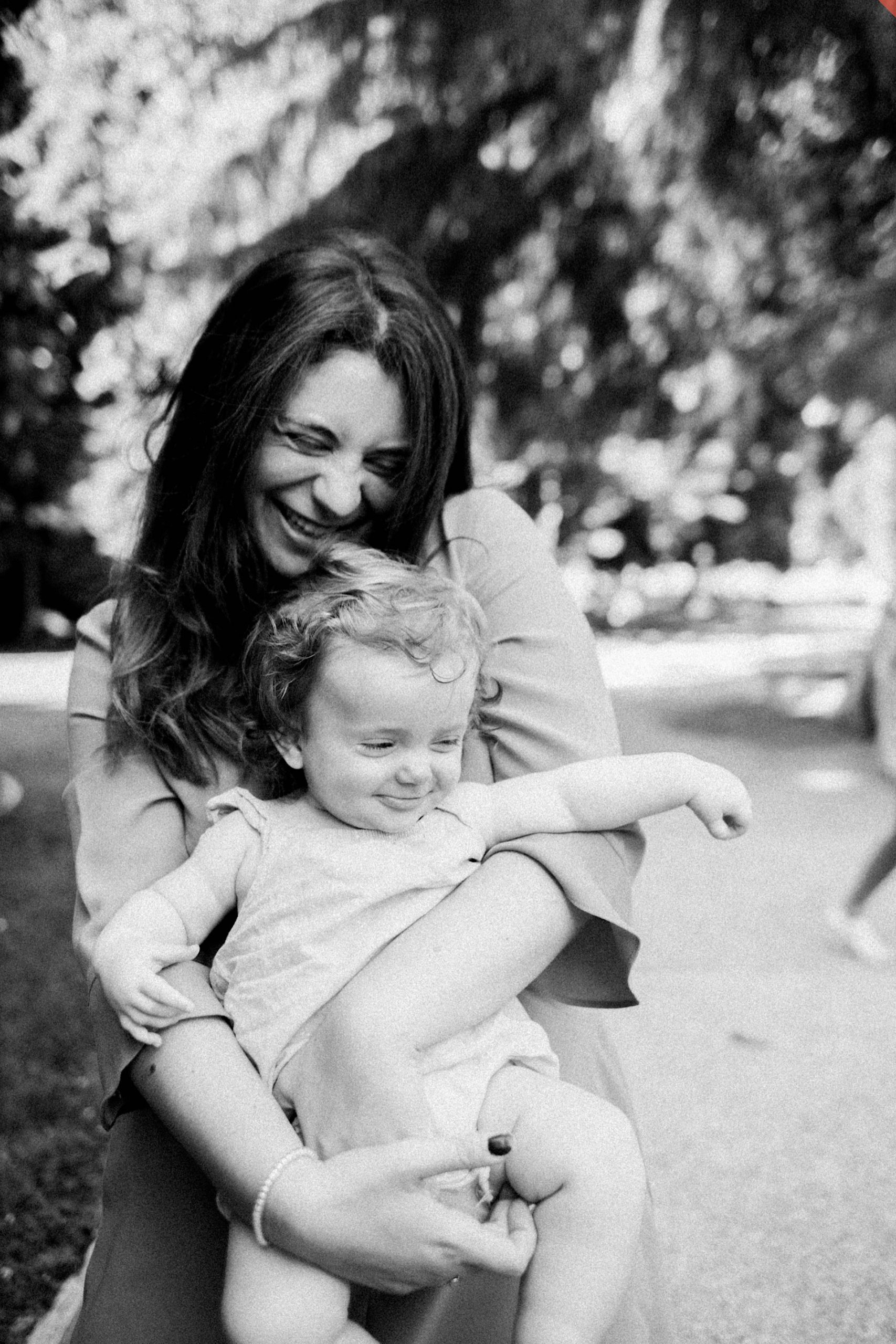 Black & white Monza Family Photography of a Mum holding her baby girl, both of them laughing.