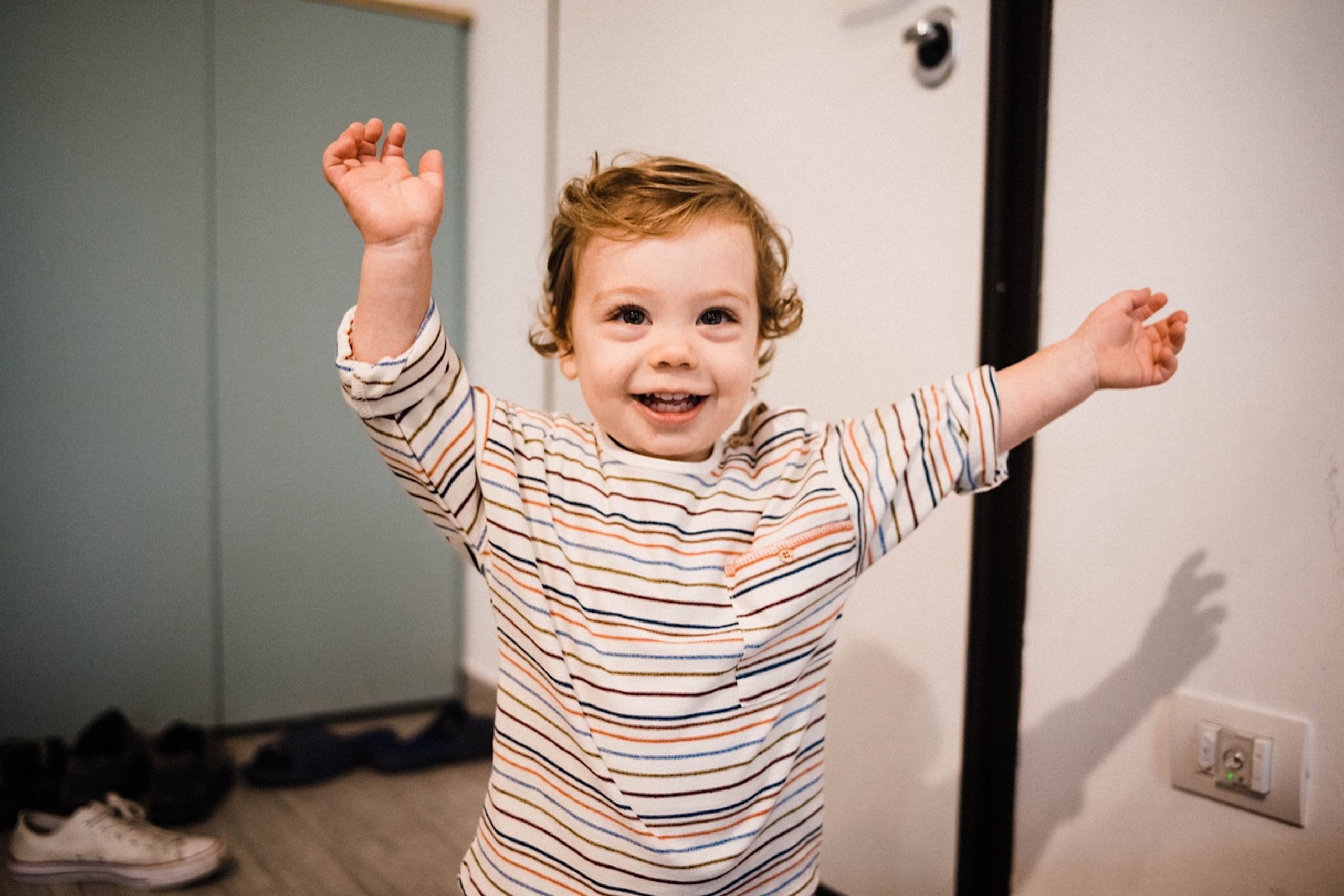 A portrait photo of a toddler smiling and cheering during an In-Home Family Photography session in Milan.